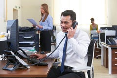 Hombre de negocios Making Phone Call en el escritorio en oficina ocupada fotos de archivo libres de regalías Hombre de negocios Making Phone Call en el escritorio en oficina ocupada fotos de archivo libres de regalías