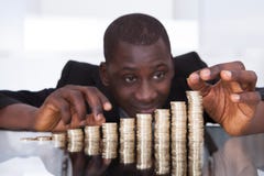 Hombre de negocios que apila monedas en fila imagen de archivo Hombre de negocios que apila monedas en fila imagen de archivo