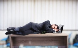 Hombre de negocios que duerme sobre un escritorio debido trabajar demasiado Fotos de archivo libres de regalías Hombre de negocios que duerme sobre un escritorio debido trabajar demasiado Fotos de archivo libres de regalías