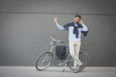 Hombre de negocios que se coloca al lado de una bici y que habla en el teléfono foto de archivo libre de regalías Hombre de negocios que se coloca al lado de una bici y que habla en el teléfono foto de archivo libre de regalías