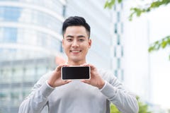 Hombre de negocios que sostiene y que muestra la pantalla del teléfono elegante Fotos de archivo Hombre de negocios que sostiene y que muestra la pantalla del teléfono elegante Fotos de archivo