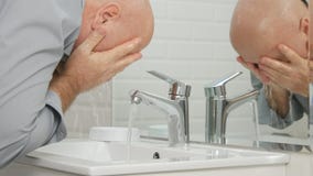 Hombre en cara moderna del lavado del cuarto de baño con el agua dulce en fregadero fotos de archivo libres de regalías Hombre en cara moderna del lavado del cuarto de baño con el agua dulce en fregadero fotos de archivo libres de regalías
