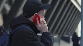 Hombre en casquillo y chaqueta negros que habla por el teléfono elegante en paisaje urbano del fondo almacen de video Hombre en casquillo y chaqueta negros que habla por el teléfono elegante en paisaje urbano del fondo almacen de video