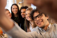 Hombre feliz que toma el selfie con los amigos en el restaurante fotografía de archivo libre de regalías Hombre feliz que toma el selfie con los amigos en el restaurante fotografía de archivo libre de regalías