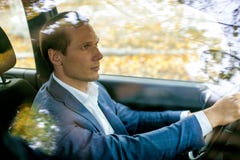 Hombre hermoso en el traje que se sienta en coche detrás de la rueda imagen de archivo libre de regalías Hombre hermoso en el traje que se sienta en coche detrás de la rueda imagen de archivo libre de regalías