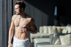 Hombre hermoso, muscular, joven que bebe su café de la mañana en un h foto de archivo Hombre hermoso, muscular, joven que bebe su café de la mañana en un h foto de archivo