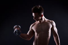 Hombre joven atlético con una pesa de gimnasia en un fondo negro Torso desnudo, cuerpo muscular Músculos fuertes del pecho y del fotos de archivo Hombre joven atlético con una pesa de gimnasia en un fondo negro Torso desnudo, cuerpo muscular Músculos fuertes del pecho y del fotos de archivo
