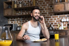 hombre joven barbudo hermoso que usa smartphone mientras que desayunando imagenes de archivo hombre joven barbudo hermoso que usa smartphone mientras que desayunando imagenes de archivo
