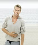Hombre joven con sonrisa en la playa Imagen de archivo libre de regalías Hombre joven con sonrisa en la playa Imagen de archivo libre de regalías