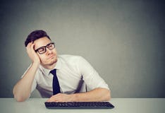 Hombre joven distraído en el escritorio de trabajo imágenes de archivo libres de regalías Hombre joven distraído en el escritorio de trabajo imágenes de archivo libres de regalías