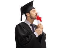 Hombre joven en un vestido y un casquillo de la graduación, besando un diploma de la licenciatura foto de archivo Hombre joven en un vestido y un casquillo de la graduación, besando un diploma de la licenciatura foto de archivo
