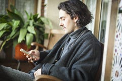 Hombre joven español que usa el smartphone que se sienta en una terraza imagenes de archivo Hombre joven español que usa el smartphone que se sienta en una terraza imagenes de archivo