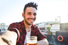 Hombre joven hermoso que toma un selfie que bebe una cerveza en la barra fotografía de archivo libre de regalías Hombre joven hermoso que toma un selfie que bebe una cerveza en la barra fotografía de archivo libre de regalías