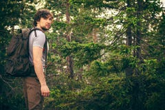 Hombre joven que camina en bosque con la mochila foto de archivo libre de regalías Hombre joven que camina en bosque con la mochila foto de archivo libre de regalías