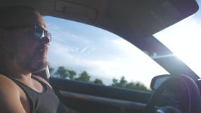 Hombre joven que conduce un coche Hombre que se sienta y que conduce en el coche Viaje de un tiempo adentro soleado almacen de metraje de vídeo Hombre joven que conduce un coche Hombre que se sienta y que conduce en el coche Viaje de un tiempo adentro soleado almacen de metraje de vídeo