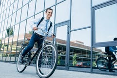 hombre joven sonriente hermoso en lentes y bici del montar a caballo del desgaste formal fotografía de archivo hombre joven sonriente hermoso en lentes y bici del montar a caballo del desgaste formal fotografía de archivo