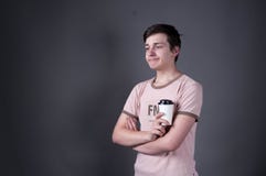 Hombre joven trastornado en la situación beige de la camiseta con los brazos cruzados, mirando lejos y sosteniendo los casquillos fotografía de archivo Hombre joven trastornado en la situación beige de la camiseta con los brazos cruzados, mirando lejos y sosteniendo los casquillos fotografía de archivo