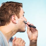 Hombre que afeita con perfil de la cara de la maquinilla de afeitar Imágenes de archivo libres de regalías Hombre que afeita con perfil de la cara de la maquinilla de afeitar Imágenes de archivo libres de regalías