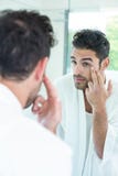 Hombre que comprueba ojos en espejo del cuarto de baño Fotos de archivo Hombre que comprueba ojos en espejo del cuarto de baño Fotos de archivo