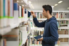 Hombre que elige el libro en biblioteca imagenes de archivo Hombre que elige el libro en biblioteca imagenes de archivo