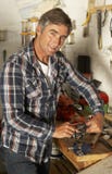 Hombre que usa el banco de trabajo en garaje imagen de archivo Hombre que usa el banco de trabajo en garaje imagen de archivo