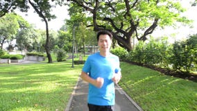 Hombre sano de la forma de vida en la ropa de deportes que funciona con y que mira su reloj en el parque en la puesta del sol Hombre sano de la forma de vida en la ropa de deportes que funciona con y que mira su reloj en el parque en la puesta del sol