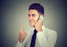 Hombre sonriente adulto que habla en el teléfono que detiene el finger imagenes de archivo Hombre sonriente adulto que habla en el teléfono que detiene el finger imagenes de archivo