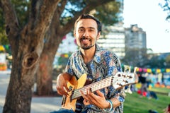 Hombre sonriente con la guitarra en la celebración al aire libre fotos de archivo Hombre sonriente con la guitarra en la celebración al aire libre fotos de archivo