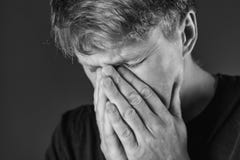 Hombre subrayado y triste que cubre su cara con las manos Tristeza, desesperación, concepto de la tragedia monocromático imagen de archivo libre de regalías Hombre subrayado y triste que cubre su cara con las manos Tristeza, desesperación, concepto de la tragedia monocromático imagen de archivo libre de regalías