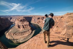 Hombre turístico que toma la foto en cámara y el trípode durante su viaje en Grand Canyon, los E.E.U.U. Fotografía de archivo Hombre turístico que toma la foto en cámara y el trípode durante su viaje en Grand Canyon, los E.E.U.U. Fotografía de archivo