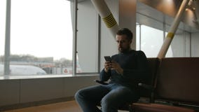 Hombre urbano de la barba que usa el teléfono elegante que viaja dentro en aeropuerto Modelo masculino hermoso almacen de video Hombre urbano de la barba que usa el teléfono elegante que viaja dentro en aeropuerto Modelo masculino hermoso almacen de video