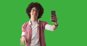 Hombre usando el teléfono móvil para la llamada video en fondo verde almacen de video Hombre usando el teléfono móvil para la llamada video en fondo verde almacen de video