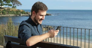 Hombre usando un teléfono elegante que se sienta en un banco Hombre usando un teléfono elegante que se sienta en un banco