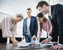 Hombres de negocios jovenes felices que se inspiran en la mesa de reuniones foto de archivo libre de regalías Hombres de negocios jovenes felices que se inspiran en la mesa de reuniones foto de archivo libre de regalías