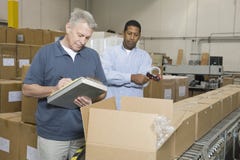 Hombres que examinan mercancías en Warehouse fotos de archivo libres de regalías Hombres que examinan mercancías en Warehouse fotos de archivo libres de regalías