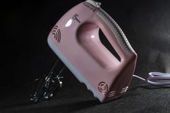 Home electric mixer of pink and white colors. On a monophonic black background. Nozzles for the mixer. Modern technologies. stock photos Home electric mixer of pink and white colors. On a monophonic black background. Nozzles for the mixer. Modern technologies. stock photos