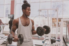 Homem africano atlético que dá certo com pesos no gym imagem de stock royalty free Homem africano atlético que dá certo com pesos no gym imagem de stock royalty free