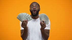 Homem afro-americano surpreendido que guarda grupos dos dólares, vencedor de loteria afortunado filme Homem afro-americano surpreendido que guarda grupos dos dólares, vencedor de loteria afortunado filme