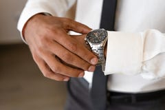 Homem bem sucedido com olhares brancos da camisa e da gravata no relógio imagem de stock royalty free Homem bem sucedido com olhares brancos da camisa e da gravata no relógio imagem de stock royalty free