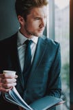Homem considerável que olha fora da janela e que olha de sobrancelhas franzidas imagens de stock Homem considerável que olha fora da janela e que olha de sobrancelhas franzidas imagens de stock