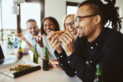 Homem de negócios afro-americano de riso que tem cervejas e sagacidade da pizza imagens de stock Homem de negócios afro-americano de riso que tem cervejas e sagacidade da pizza imagens de stock