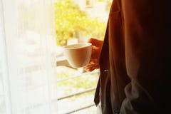 Homem de negócios com suporte e guardar do terno o copo de café foto de stock royalty free Homem de negócios com suporte e guardar do terno o copo de café foto de stock royalty free