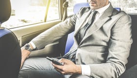 Homem de negócios considerável novo que senta-se no táxi de táxi com telefone imagem de stock royalty free Homem de negócios considerável novo que senta-se no táxi de táxi com telefone imagem de stock royalty free