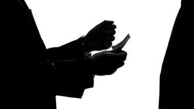 Homem de negócios criminoso nas algemas que dão o subôrno para a liberação da prisão, corrupção imagens de stock Homem de negócios criminoso nas algemas que dão o subôrno para a liberação da prisão, corrupção imagens de stock