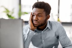 Homem de negócios forçado com o computador no escritório imagem de stock Homem de negócios forçado com o computador no escritório imagem de stock