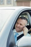 Homem de negócios no carro que fala no telefone móvel fotografia de stock Homem de negócios no carro que fala no telefone móvel fotografia de stock