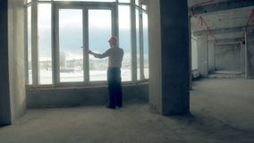 Homem de negócios novo empreendedor bem sucedido que fala no telefone perto da janela panorâmico na construção nova, escritório i vídeos de arquivo Homem de negócios novo empreendedor bem sucedido que fala no telefone perto da janela panorâmico na construção nova, escritório i vídeos de arquivo