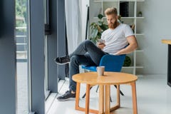 Homem de negócios novo farpado que trabalha no escritório moderno Equipe o t-shirt branco vestindo e notas da fatura nos originai Fotografia de Stock Royalty Free Homem de negócios novo farpado que trabalha no escritório moderno Equipe o t-shirt branco vestindo e notas da fatura nos originai Fotografia de Stock Royalty Free