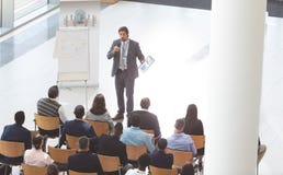 Homem de negócios que fala na conferência ao guardar a tabuleta e o microfone digitais no seminário do negócio fotos de stock royalty free Homem de negócios que fala na conferência ao guardar a tabuleta e o microfone digitais no seminário do negócio fotos de stock royalty free