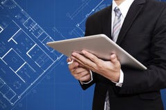 Homem de negócios que trabalha na tabuleta digital com fundo arquitetónico do desenho do plano do modelo, arquiteto, concep do ne fotos de stock Homem de negócios que trabalha na tabuleta digital com fundo arquitetónico do desenho do plano do modelo, arquiteto, concep do ne fotos de stock